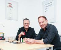 Tobias Kämmerer und Thomas Esche sitzen an einem Bürotisch.